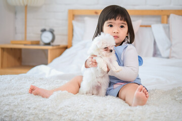 The little girl cradled the cute white dog in her arms its fur soft against her cheek.