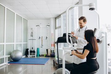 Young woman making spine examination in diagnostics machine with physiotherapist