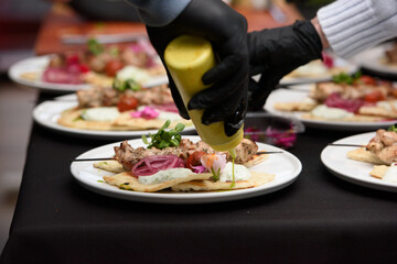 the chef in the restaurant prepares souvlaki with pita and tzatziki sauce