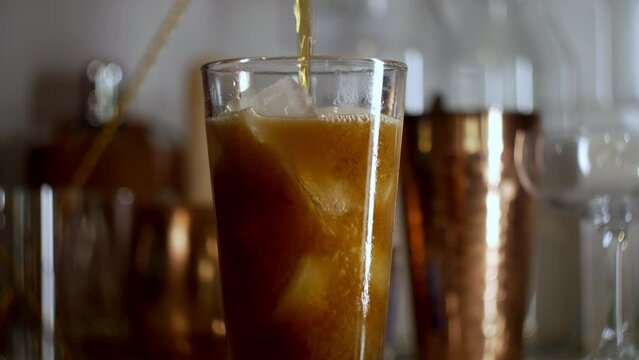 Fizzy bubbly soda pouring in to pint glass at home bar