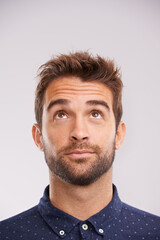 Obraz premium Thinking, looking up and man in studio with solution, ideas and relax with eyes and mockup. Isolated, gray background and male model face think and distracted with planning with decision alone