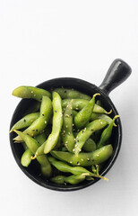 japanese edamame beans snack in black ceramic bowl on white background