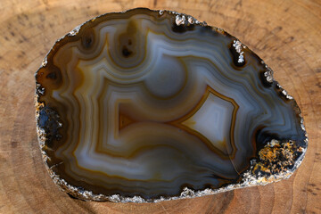 Piękny  unikatowy ciemny kamień szlachetny - agat szlifowany. Ujęcie z bliska na drewnianej desce 