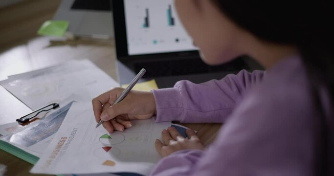 Footage of young Asian woman, freelance data scientist work remotely at home business analyst, Female writes notes on paper. IT Technician. Telework concept.