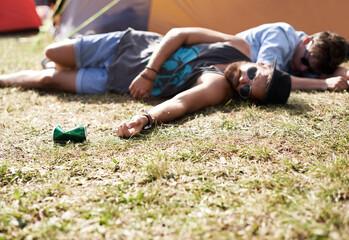 Drunk, sleeping and men on camping ground at a music festival with alcohol. Field, drinking and...