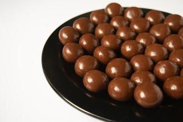 chocolate balls on a black plate on a white background