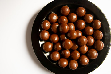 chocolate balls on a black plate on a white background