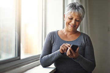 Window, smile and senior woman with a smartphone, connection and social media at home. Mature female, person and old lady with a cellphone, email and mobile app with network, happiness and typing