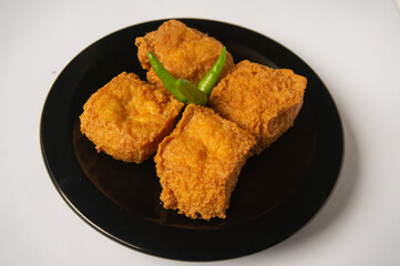 Crispy fried tofu on a black plate on a white background