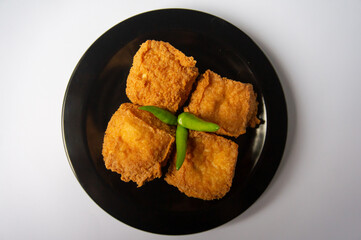 Crispy fried tofu on a black plate on a white background