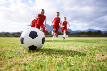 Running, teamwork and sports with children and soccer ball on field for training, competition and...