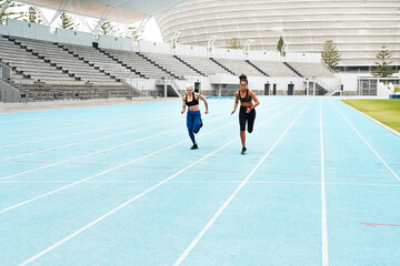 Be stronger than your excuses. Full length shot of two attractive young athletes running a track field together during an outdoor workout session.