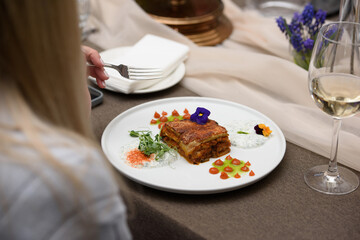 portion of traditional greek moussaka in white plate on a table in a restaurant