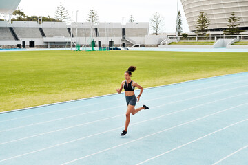 Running is my escape. Full length shot of an attractive young athlete running a track field alone during a workout session outdoors.