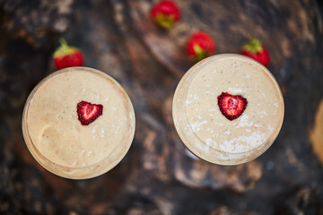Dessert is even better when its shared. a freshly made cream snack served in a glass with strawberries on a table.