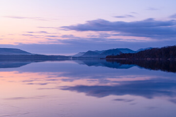 風景を湖面に反射する早朝の湖。北海道の屈斜路湖。