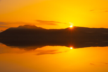 山間の湖の日の出の時の黄金色の風景。北海道の屈斜路湖。