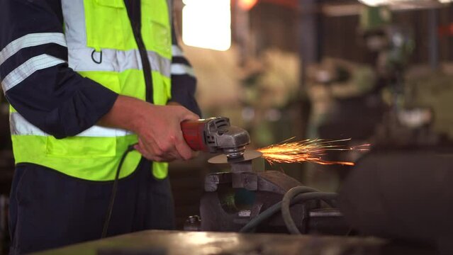 Heavy industry metal work worker using metal grinder machine sharpening a metal pipe close up.