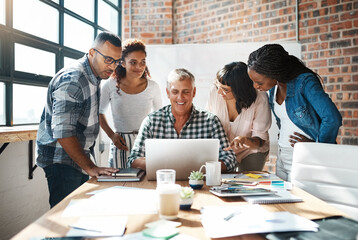 Grab your team and get it done. a group of colleagues using a laptop together in a modern office.