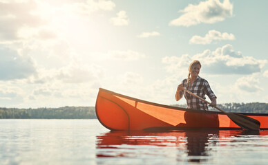 This is how she does weekends. an attractive young woman spending a day kayaking on the lake.