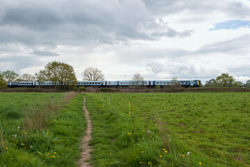 Fototapeta na wymiar SWR train travelling through the countryside on a stormy spring day
