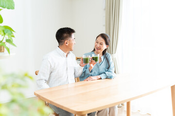 Obraz premium リビングで青汁を持つシニア夫婦