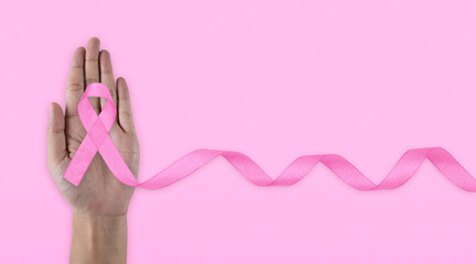 Hands holding pink ribbon on backgrounds. Breast cancer awareness and October Pink day, world cancer day. Top view.