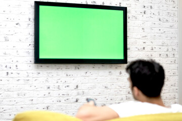 Man sitting on the couch and watching tv. Green screen concept	