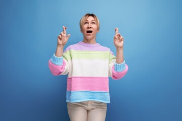 surprised blond woman in casual outfit showing hands up on blue background with copy space