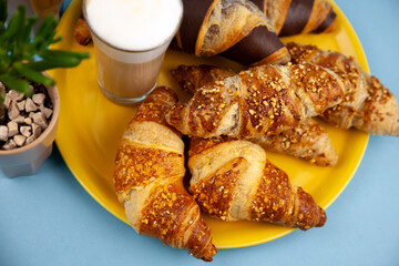 Chocolate croissants or croissant with nut crumbs on a plate. Delicious breakfast on the table. Tasty sweet baking dessert for coffee. Food background. Fresh buttery croissants rolls
