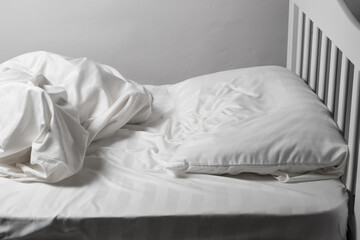 Fototapeta na wymiar Unmade bed, satin white linen, white bed, pillow and blanket