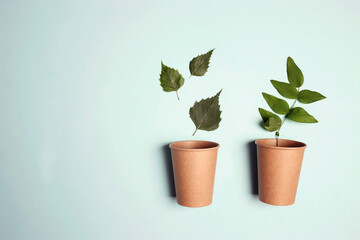 Eco-friendly coffee to go cups with green leaves on blue background.