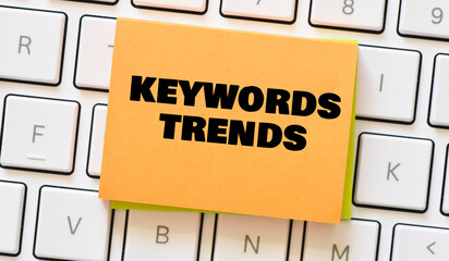 KEYWORDS TRENDS words on a small piece of paper placed on a white keyboard.