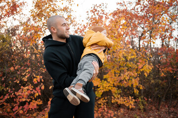 Happy father and little son having fun outdoors over autumn park background. Cute little boy playing with dad outdoors. Autumn fashion. Family, childhood and fatherhood