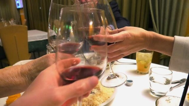 Four hands with red wine, cheers in a restaurant.