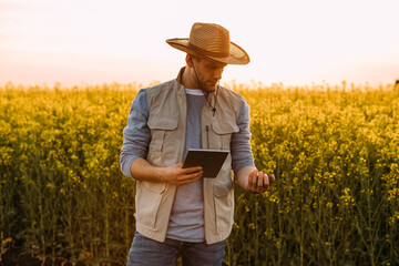 A farmer is standing in the field and holding soil and tablet.