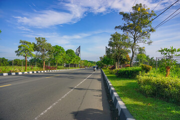 Empty highway condition in the morning with clear sky and beautiful park by the roadside.