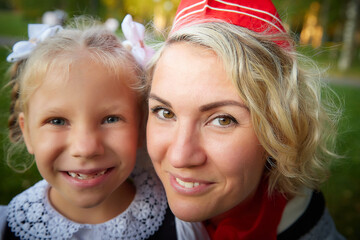 Young and adult schoolgirl on September 1. Generations of schoolchildren of USSR and modern Russia. Female pioneer in red tie and October girl in modern uniform. Mother and daughter having fun