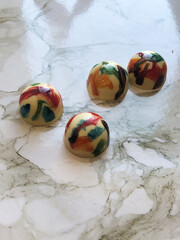 Round multicolored handmade candies on a marble surface