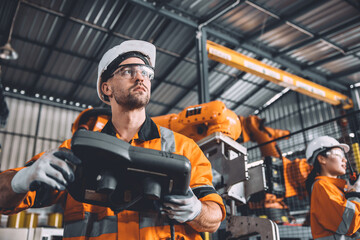 Engineer team working with robot welding in automation factory. People worker in safety suit...