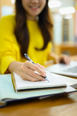 Select focus on hand. Young female student doing class assignment, preparing for exam, ,making notes on notepad