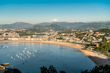 Fototapeta premium San Sebastian, SPAIN - July 09 2022: High angle view of San Sebastian - Donostia city at sunset. Situated in north of Spain, Basque Country. Famous travel destination. View of La Concha Bay