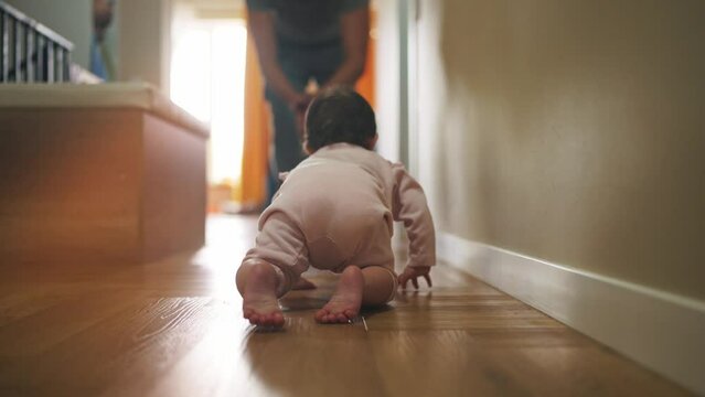 father teaches baby to crawl. happy family a first steps kid dream concept. father helps baby newborn crawling on the floor in house. baby girl crawling on the floor lifestyle takes her first steps