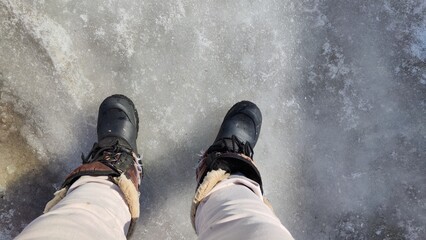 Feet of Hunter or fisherman in big warm boots on a winter day on snow. Top view. Fisherman on the...