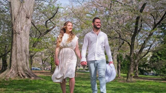 A married couple walking at Cherry Blossom Park in Washington DC holding hands