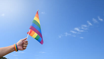 Rainbow flag raising against cloudy and bluesky background, copy space, concept for LGBT celebrations in pride month, June, around the world.