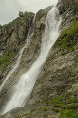 Obraz premium Concept of great nature mountain range. Amazing view of caucasus mount and Sofia waterfalls landscape, fast river and big stones with cloudy sky as background at rainy summer day. Russia, Arkhyz