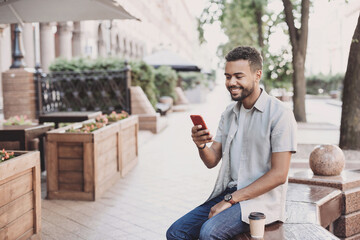Young student man using smartphone in a city. Smiling joyful guy summer portrait. Handsome business...