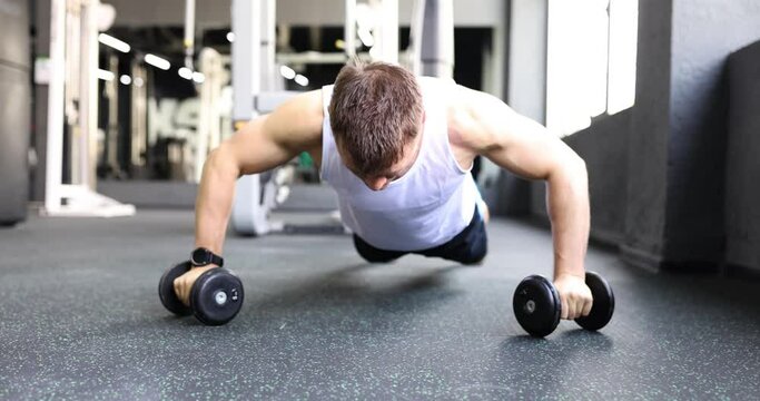 Man athlete doing push ups on dumbbells in gym 4k movie slow motion. Regular sorting load for body concept