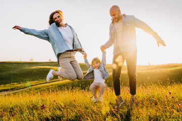 Happy family enjoying sunny day on green meadow jumping  having fun. Happy woman with her bearded...
